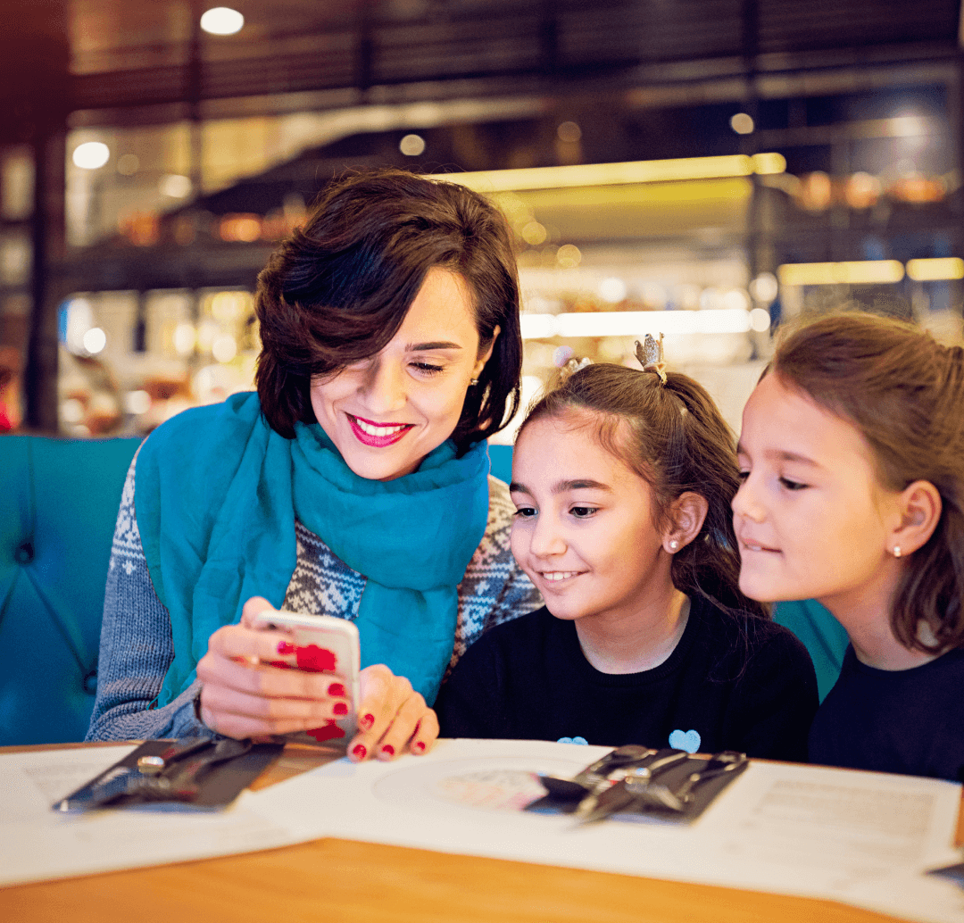 une mère de famille en train de commander un menu avec l'application cookie menu sur son téléphone mobile avec ses deux petites filles